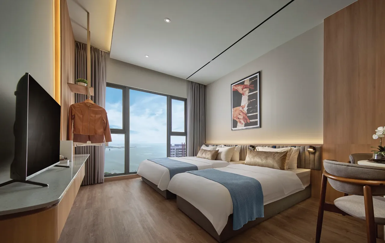 Twin bedroom configuration with sea view, warm timber and neutral palette